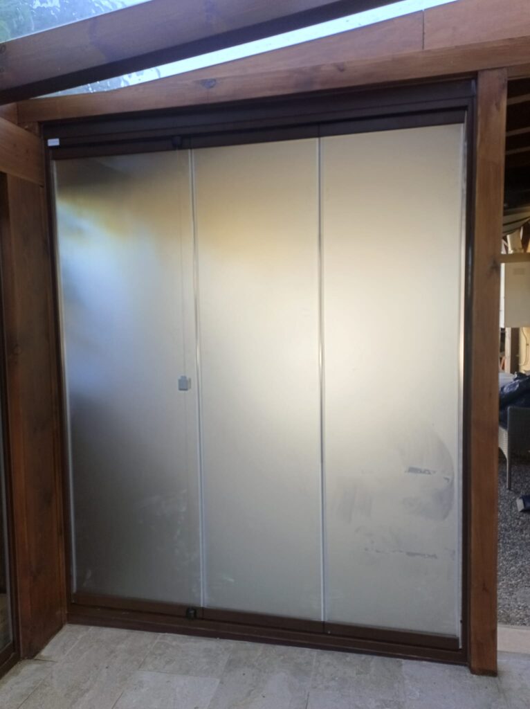 Cerramiento de terraza a medida con vidrio translúcido e imitación madera. Aricruz Aluminio.
