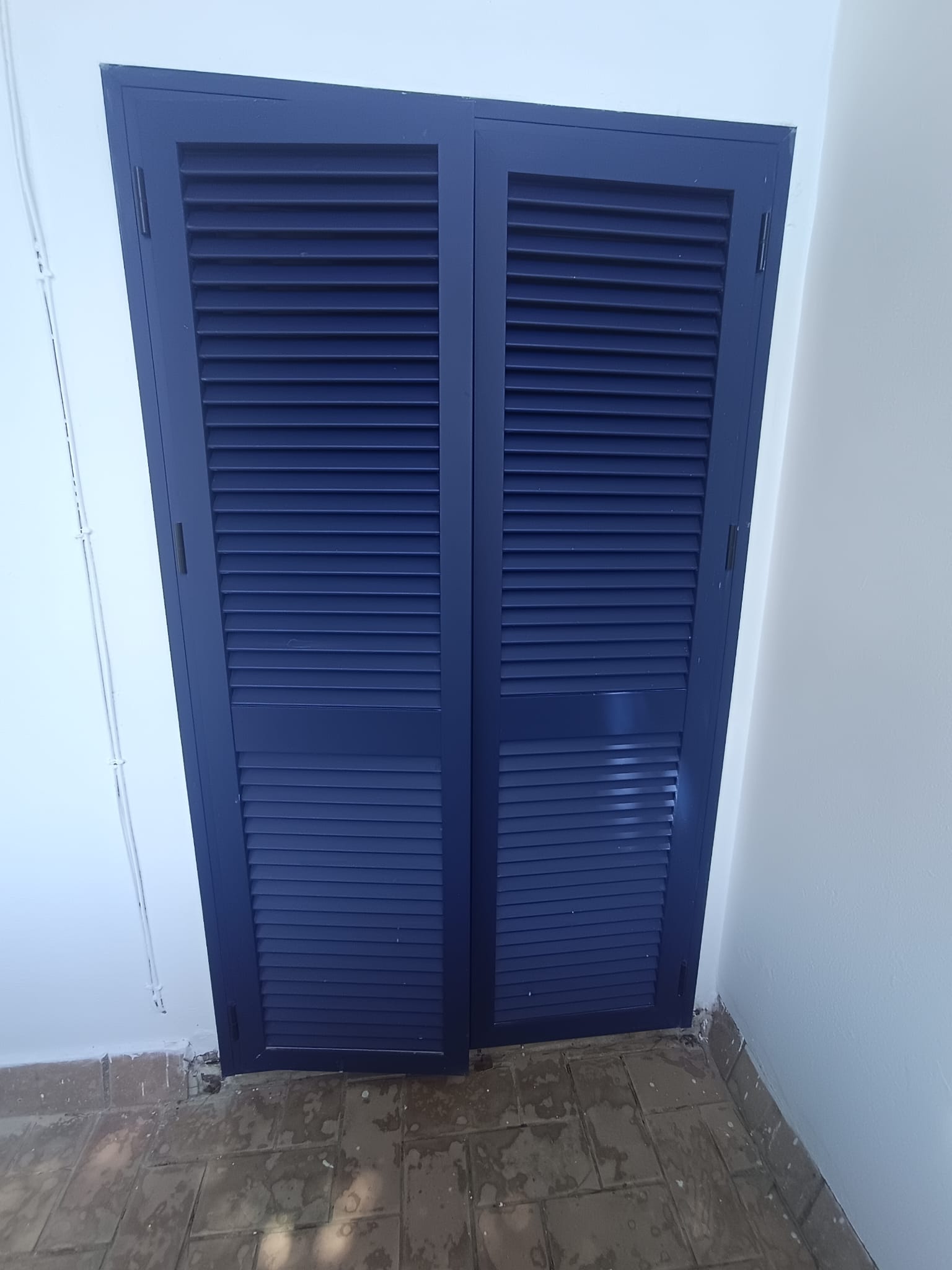 Puerta azul de aluminio con lamas a medida
